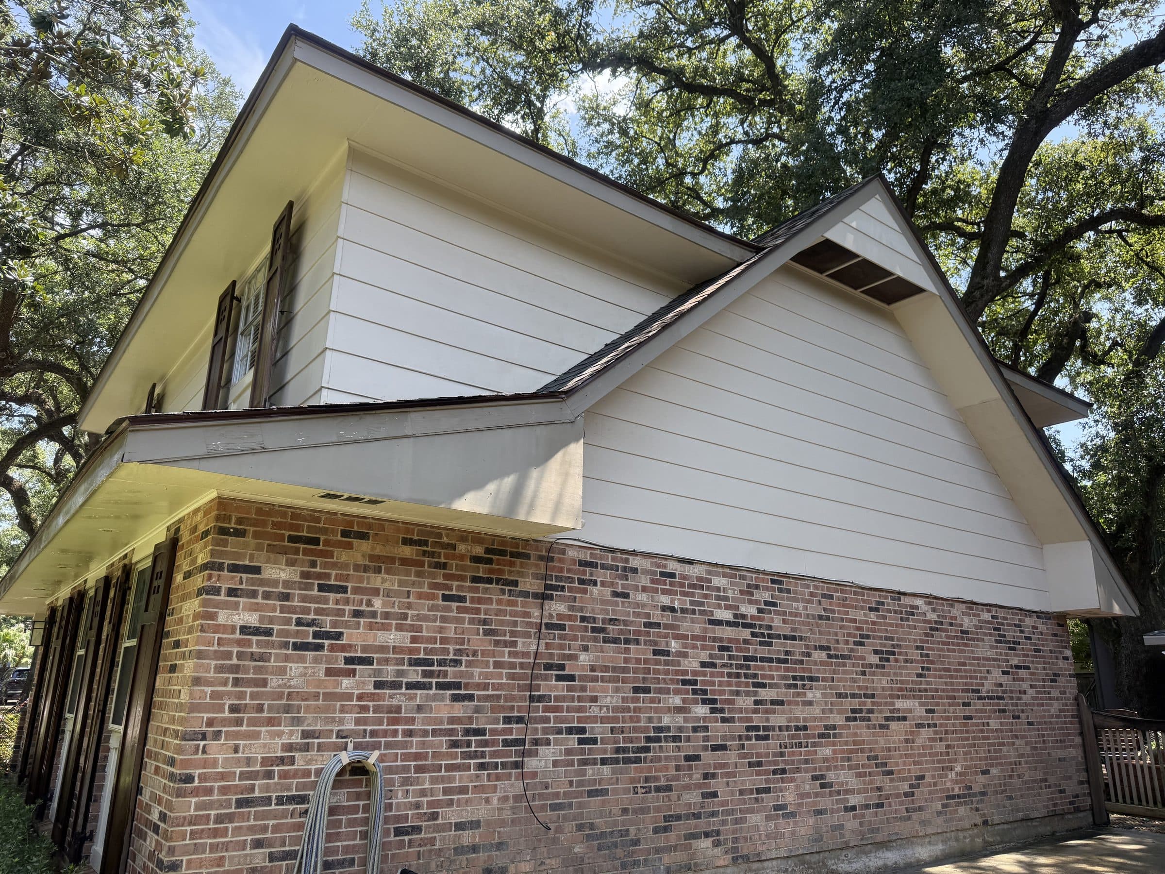 Cream siding gable over brick, washed clean on a Gretna home